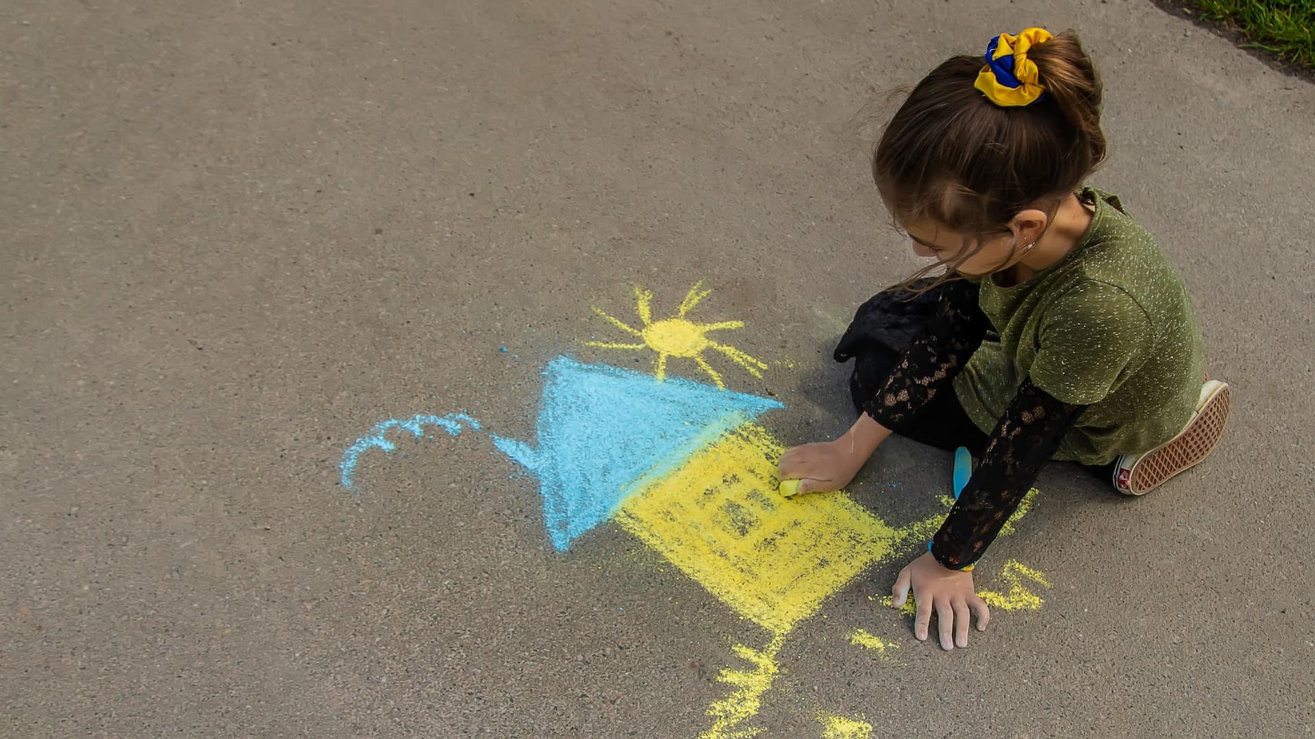Children draw the Ukrainian flag house on the pavement. Selective focus.